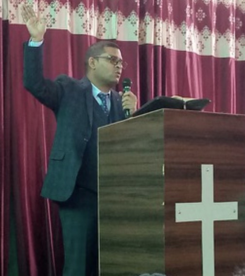 Pastor Mange Singh preaching at a church pulpit